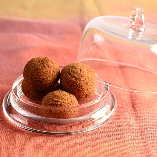 LEGÙ Soft Almond Pastries: 4 gluten-free and plant-protein-rich treats, on a glass stand with a dome, on an orange cloth.