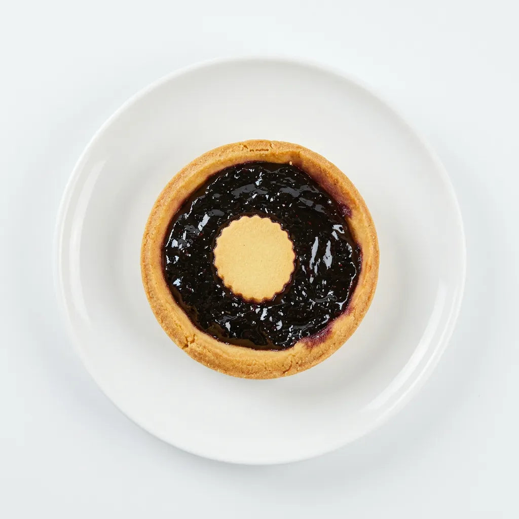 Crostatina ai frutti di bosco LEGÙ su piatto bianco, un dolce con base ai legumi, senza glutine e ricco di proteine vegetali.