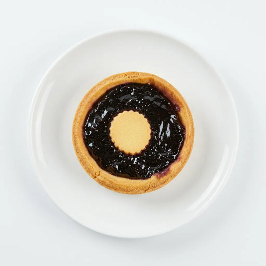 Tarta de frutos del bosque LEGÚ en plato blanco, un postre con base de legumbres, sin gluten y rico en proteínas vegetales.