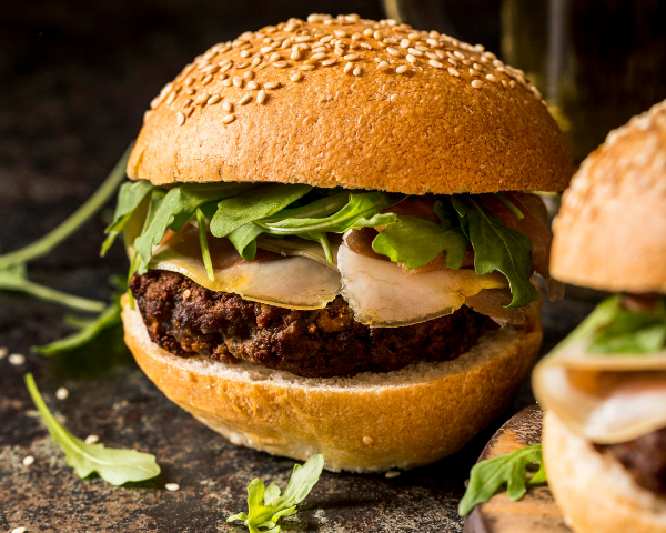 Burger di legumi Legù in panino gourmet con insalata fresca e ingredienti naturali.