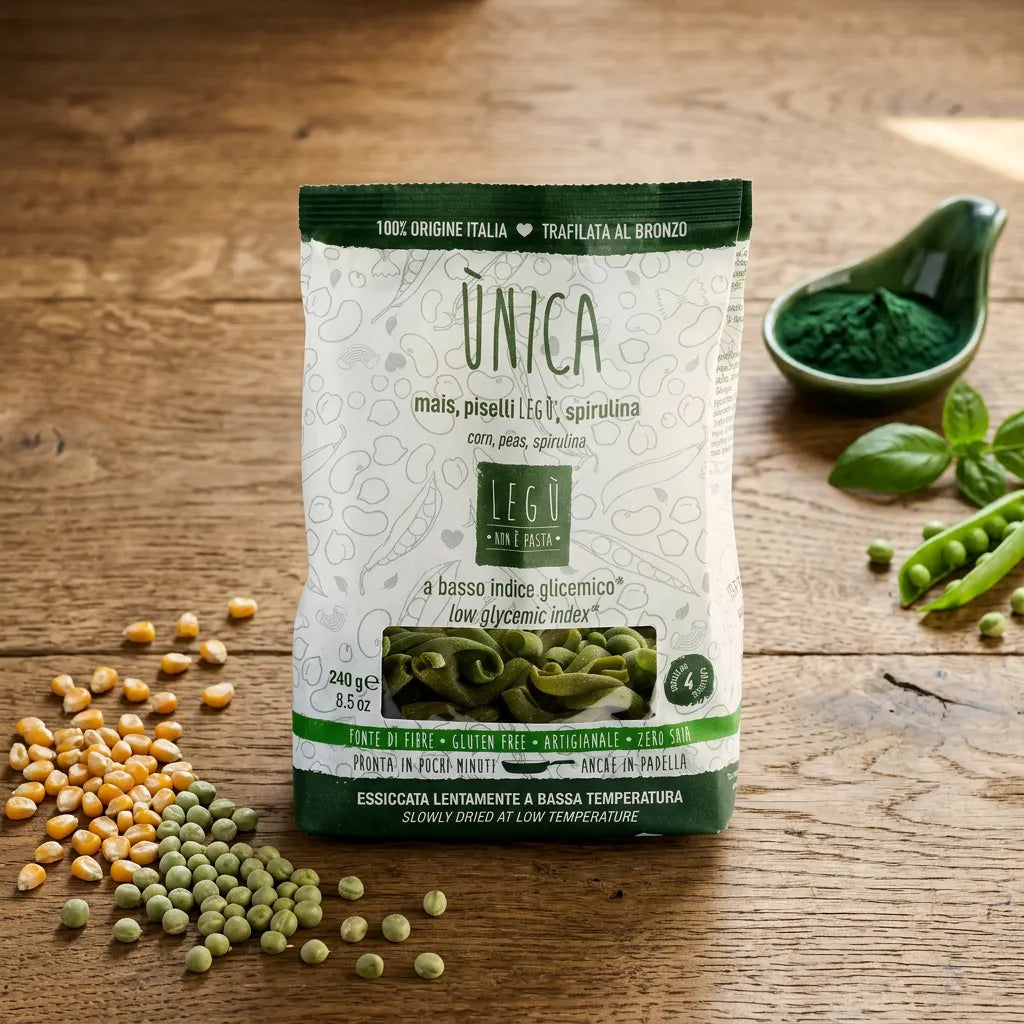 Confezione di pasta LEGÙ ÙNICA con mais, piselli e spirulina su tavola di legno, con chicchi di mais e piselli freschi accanto. Un'opzione di pasta senza glutine e ricca di proteine vegetali.