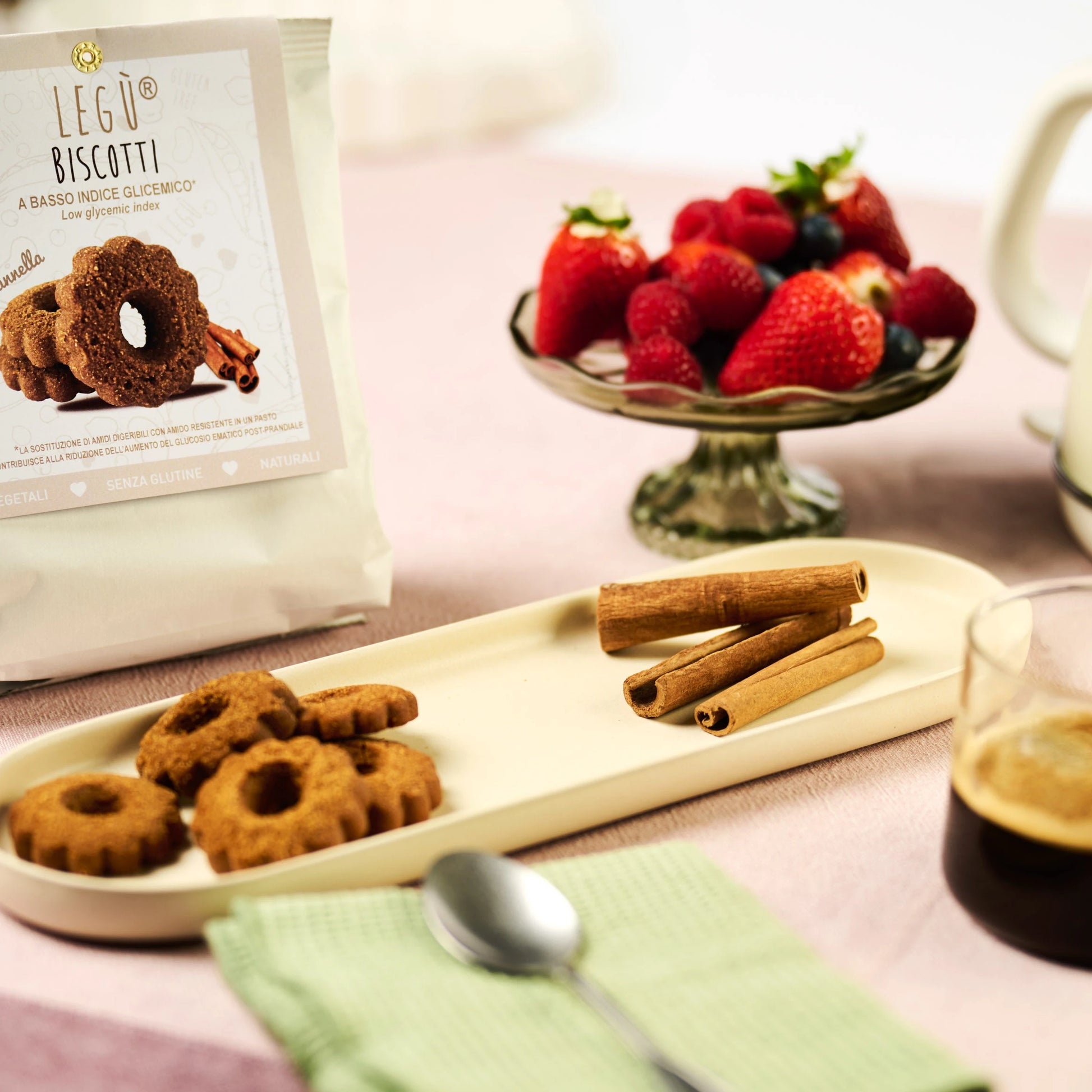 Confezione LEGÙ Biscotti di legumi alla cannella, a basso indice glicemico e senza glutine, con biscotti sul piatto, frutta e caffè.