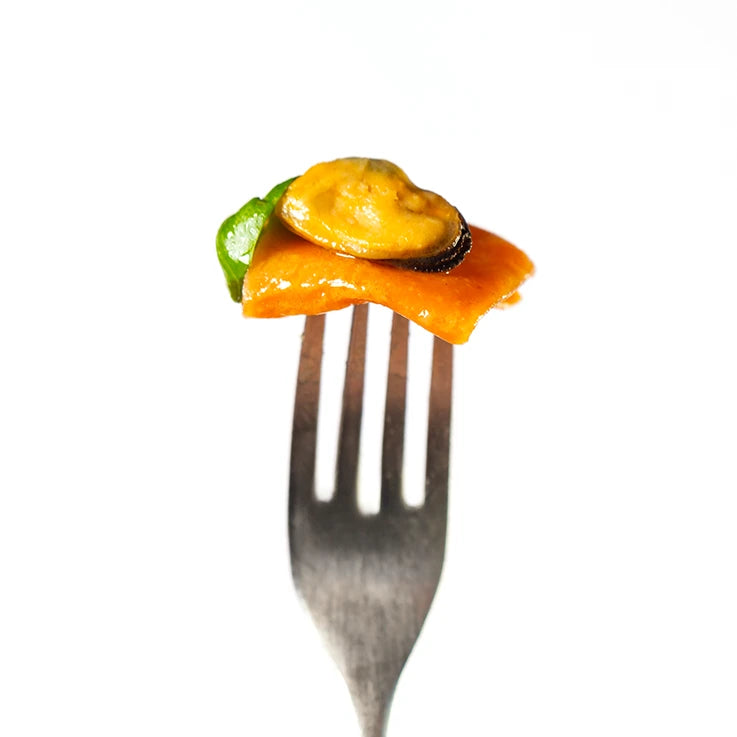 Un pacchero LEGÙ ÙNICA con mais, lenticchie rosse e pomodoro, senza glutine e ricco di proteine vegetali, infilzato in una forchetta con cozza e basilico, su sfondo bianco.