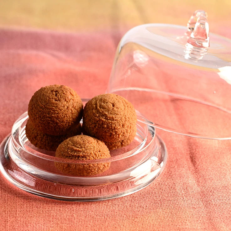 Pasticcini morbidi all'arancia LEGÙ senza glutine, ricchi di proteine vegetali da legumi, in alzatinacristallo su tessuto arancione.