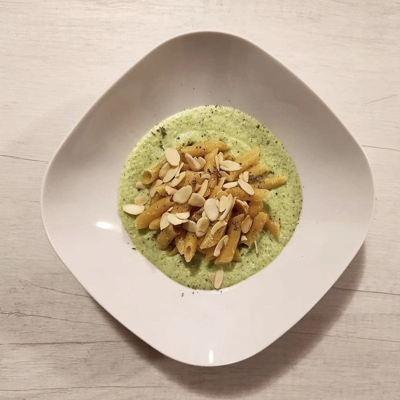 LEGÙ Penne (fagioli, ceci, lenticchie, piselli) decorticate, in un piatto bianco, con crema di legumi e mandorle. Ottimo per ricette ricche di proteine vegetali.