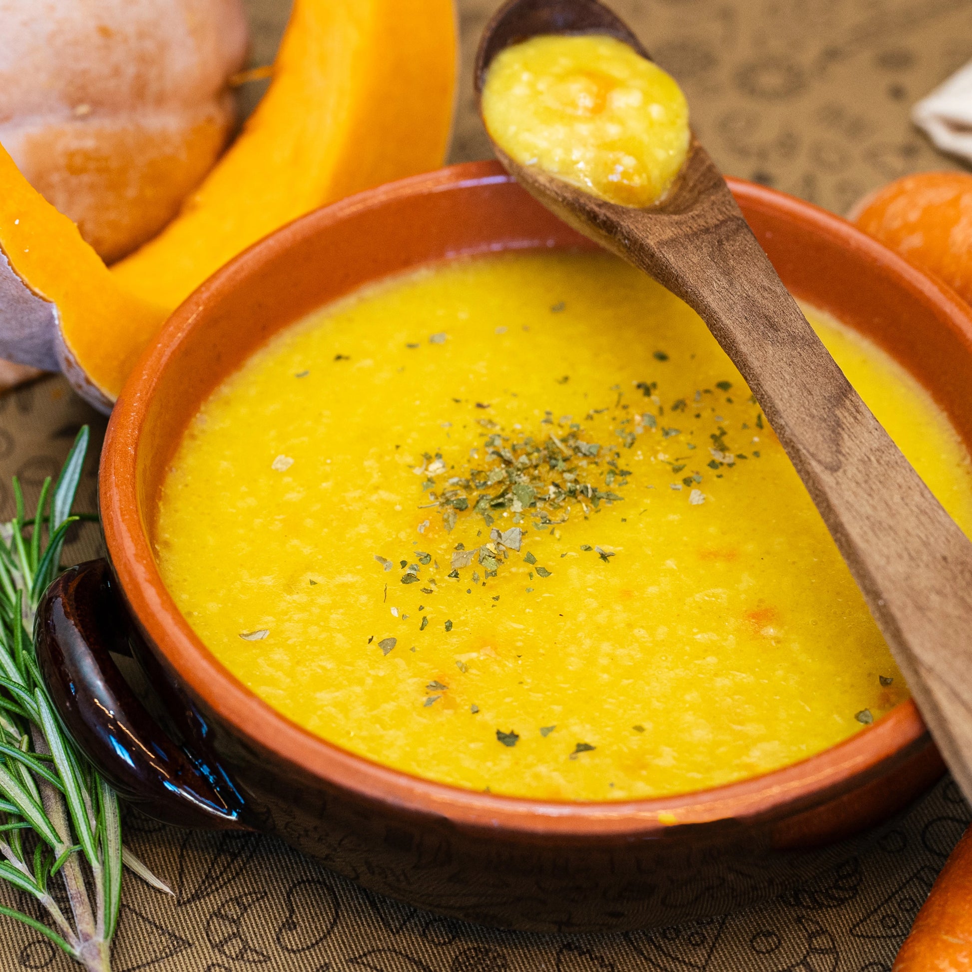 Piatto fumante di Zuppa Delicata Bio LEGÙ con legumi decorticati, carote e zucca, guarnita con erbe, ingredienti freschi.