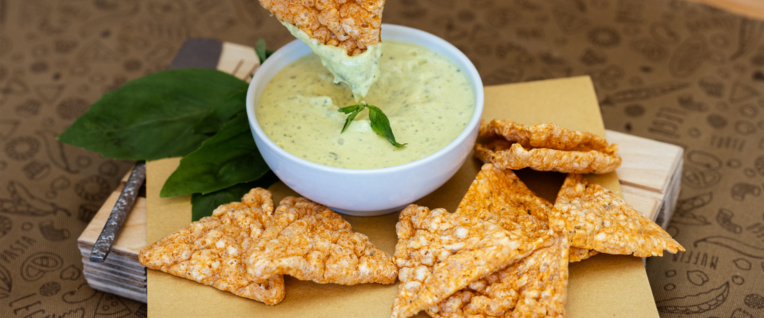 Triangoli di legumi Legù serviti con salsa cremosa verde per un aperitivo originale e gustoso.