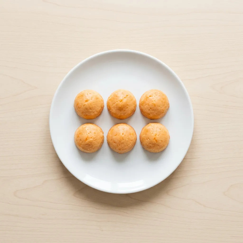 Pasticcini Morbidi all'Arancia LEGÙ su piatto bianco, dolcetti di legumi senza glutine e con proteine vegetali.